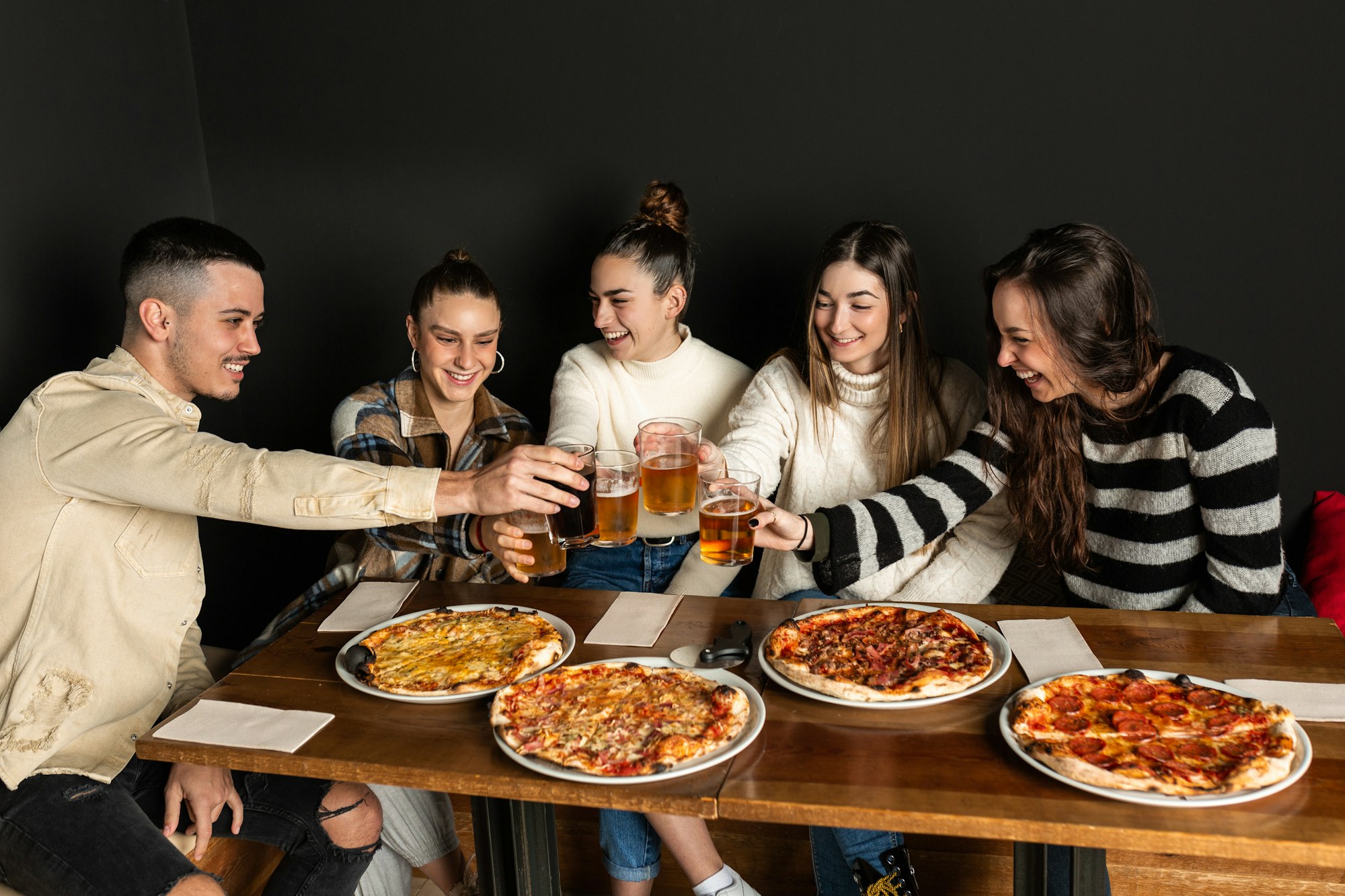 group of friends toasting with glasses of beer and soft drink in a pizzeria